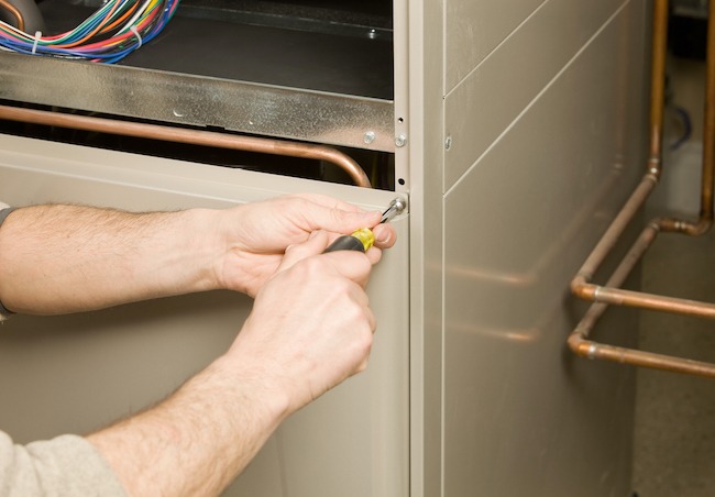 technician using a screwdriver on an air conditioning unit